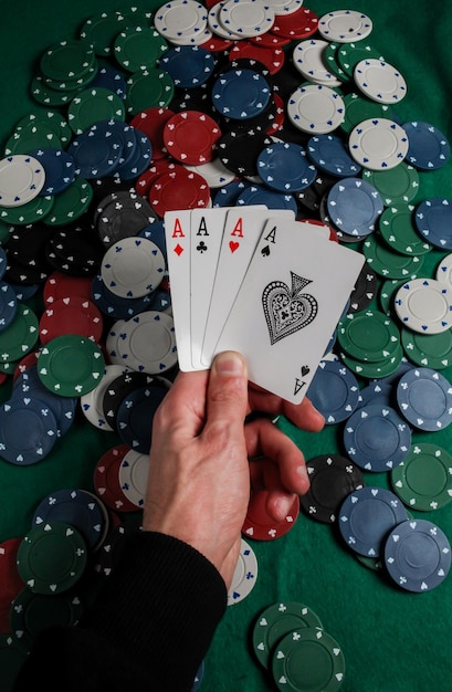 Senior Poker. The player holds in his hand four playing cards, four aces. Casino chips background