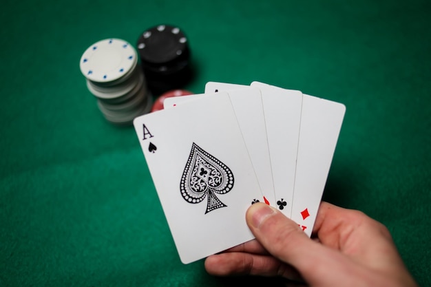 Senior Poker. The player holds in his hand four playing cards, four aces. Casino tabke background