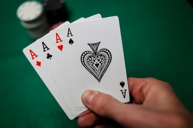 Senior Poker. The player holds in his hand four playing cards, four aces. Casino tabke background