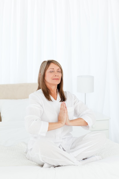 Senior practicing yoga on her bed