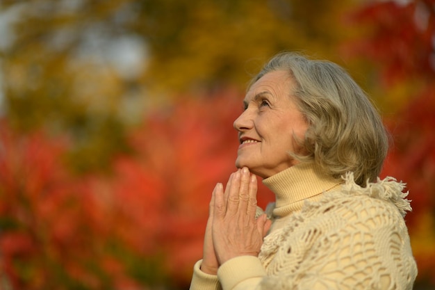 Senior smiling woman in park praying