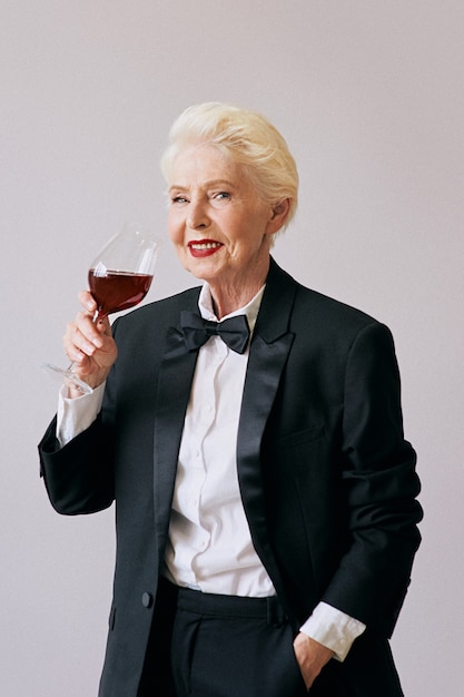 senior sommelier woman in tuxedo with glass or red wine