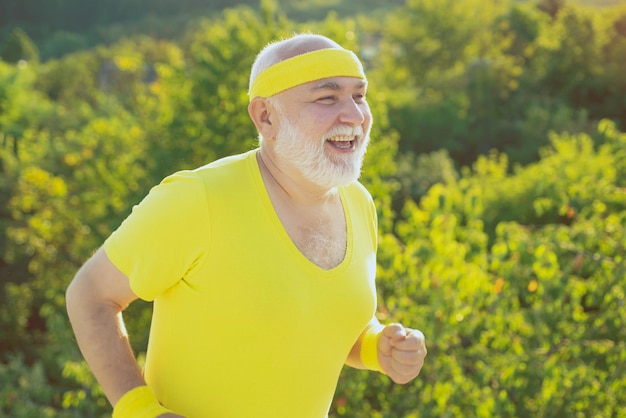 Senior sportsman jogging outdoors and enjoying sunny day Senior man is doing sport outdoors Senior man hiking in summer in nature