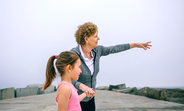 Senior sportswoman pointing while little girl is looking