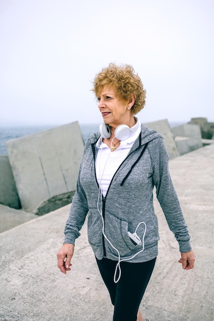 Senior sportswoman walking by sea concrete pier