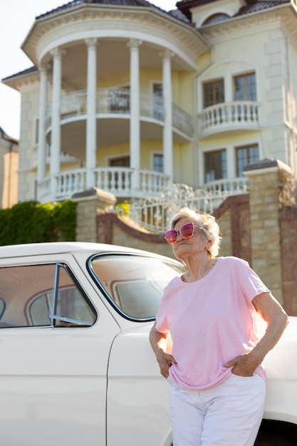 Senior traveler standing nest to her car