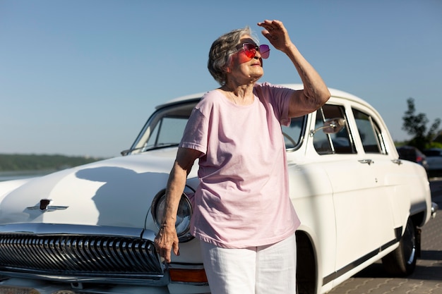 Senior traveler standing nest to her car