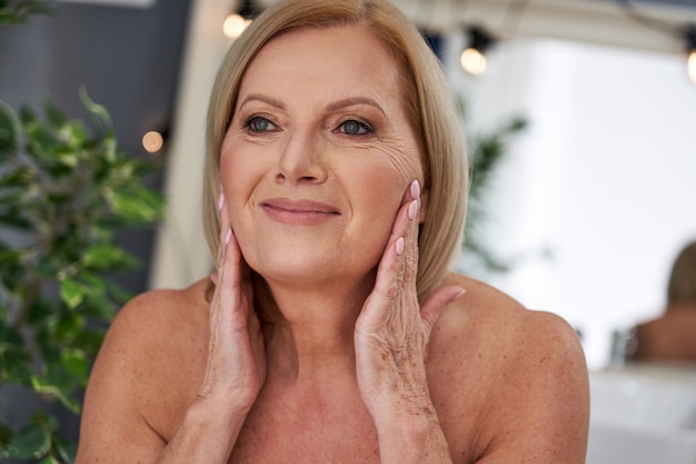 senior woman applying face cream in the bathroom