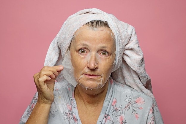 senior woman applying a facial mask napkin