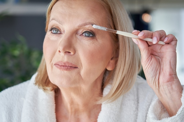 senior woman applying makeup in the bathroom