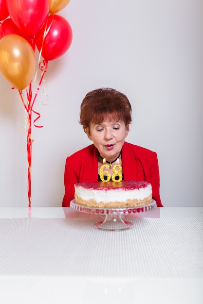 Senior woman blowing out candles on cake