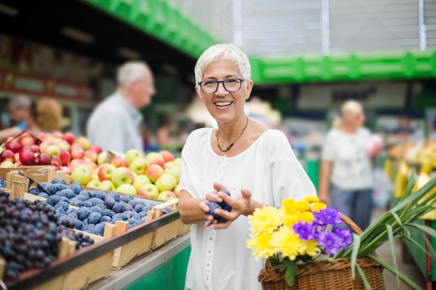 Senior woman buying fruit on market