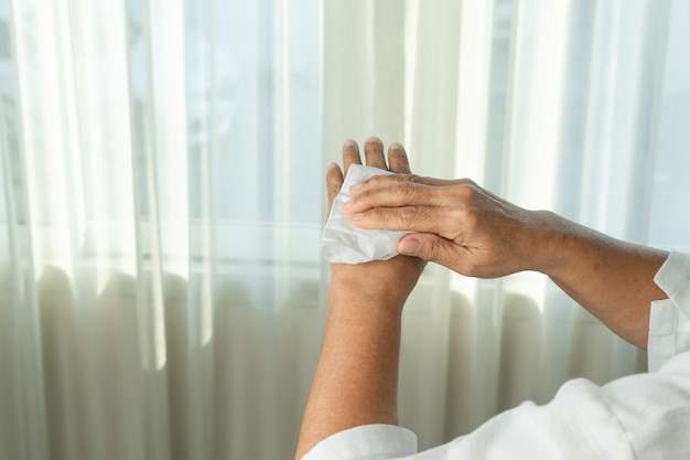 Senior woman cleaning her hands with white soft tissue paper. isolated on a white backgrounds