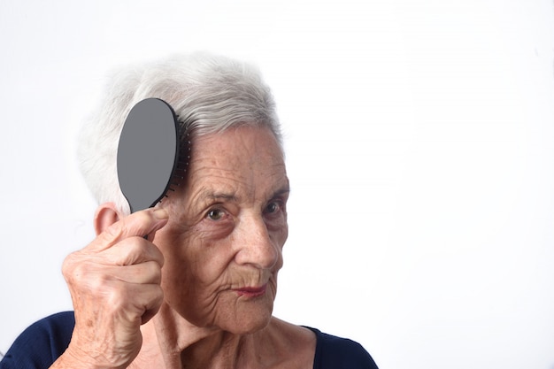 Senior woman combing her hair on white background