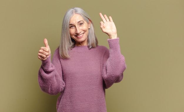 Senior woman feeling happy, amazed, satisfied and surprised, showing okay and thumbs up gestures, smiling