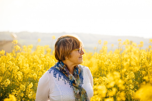 Senior woman in a field of yellow flowers