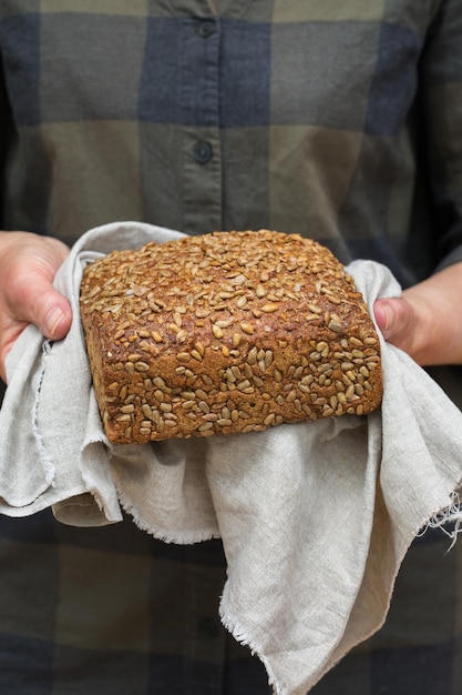 Senior woman hands holding freshly baked loaf of rye bread