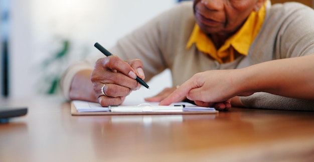 Senior woman hands and writing on contract form or application for retirement plan or insurance at home Closeup of elderly female person signing documents paperwork or agreement on table at house