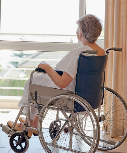 Senior woman in her wheelchair looking out the window