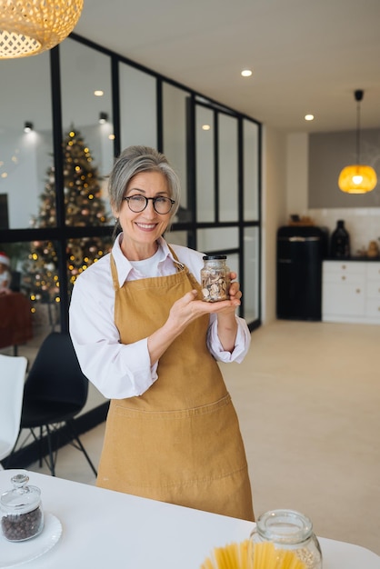 Senior woman holds glass jar with cereals in his hands