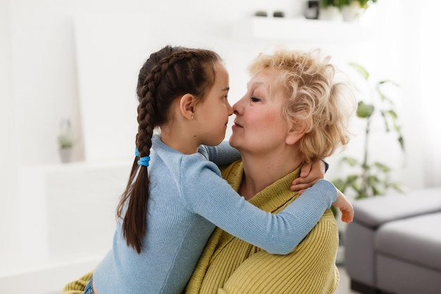 Senior woman hugging granddaughter while sitting on sofa at home