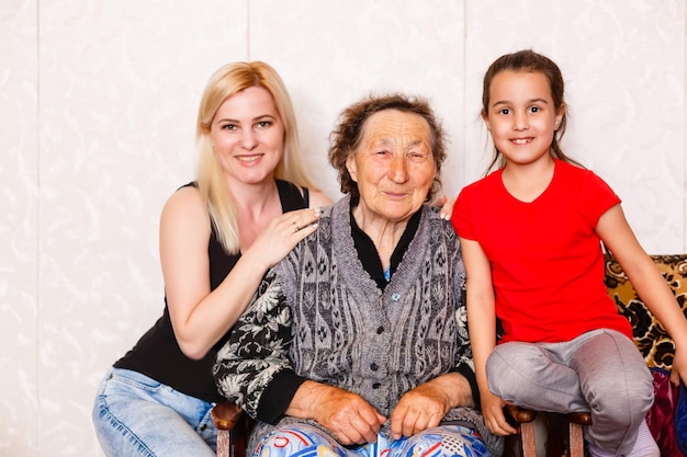 Photo senior woman hugging granddaughter while sitting on sofa at home