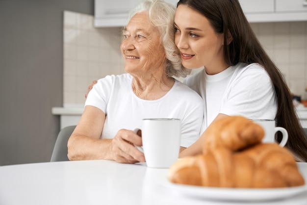 Senior woman hugging with granddaughter in kitchen