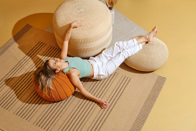 Senior woman is lying on the floor with her legs on padded stool in relaxing environment