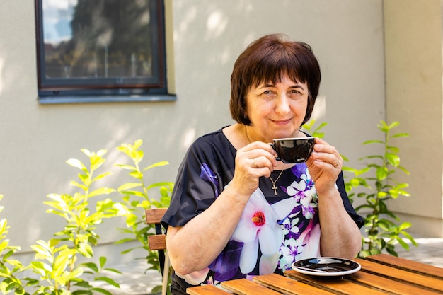 The senior woman is relaxing in the street cafe