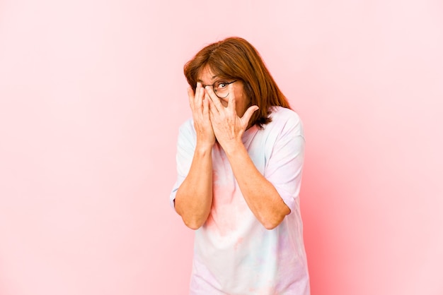 Senior woman isolated blink through fingers frightened and nervous