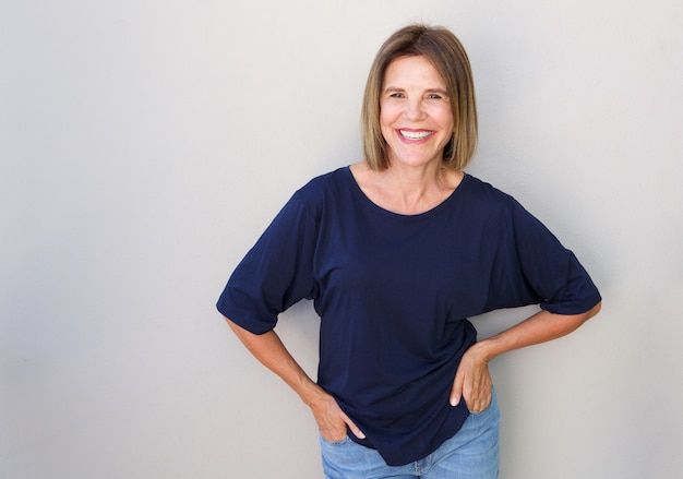 Senior woman laughing against gray wall