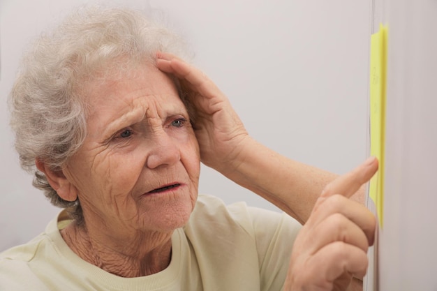 Senior woman looking at reminder note indoors Agerelated memory impairment