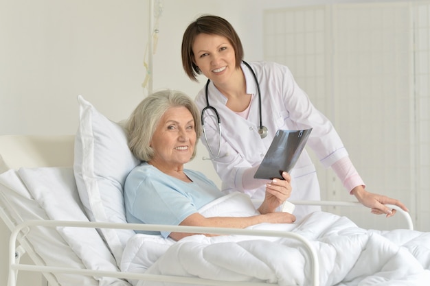 Senior woman portrait in hospital with caring doctor