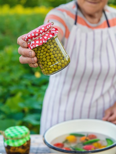 Senior woman preserving vegetables in jars Selective focus