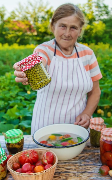 Senior woman preserving vegetables in jars Selective focus