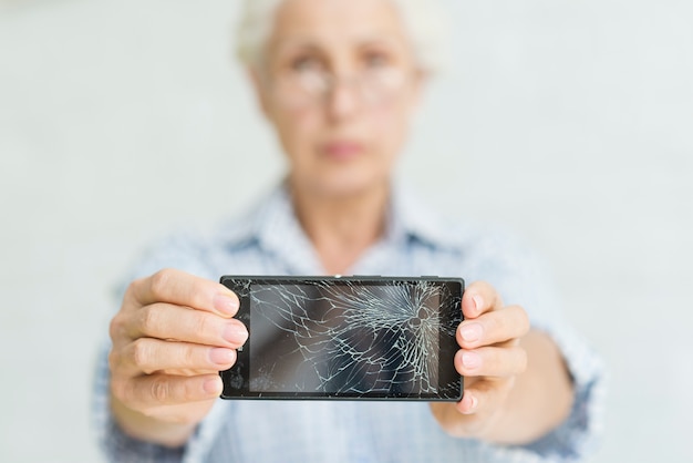 Senior woman showing smartphone with cracked screen