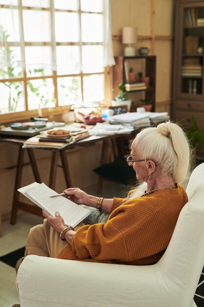 Photo senior woman sitting indoors reading book peacefully