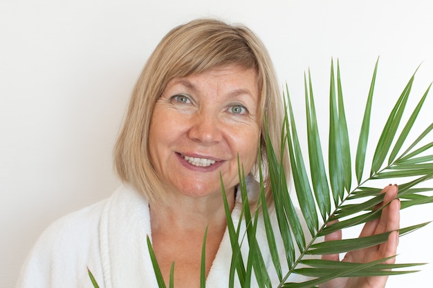 Senior woman smiling Anti-age concept with palm leaf. Mature woma face after spa treatment. Old age in joy, plastic surgery clinic, cutie grandmother, cosmetology, new senior, pensioner, mature people