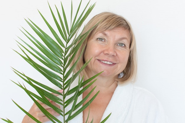 Senior woman smiling Anti-age concept with palm leaf. Mature woma face after spa treatment. Old age in joy, plastic surgery clinic, cutie grandmother, cosmetology, new senior, pensioner, mature people