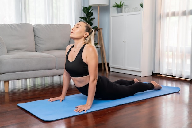 Senior woman in sportswear being doing yoga in meditation posture on exercising mat at home Healthy senior pensioner lifestyle with peaceful mind and serenity Clout