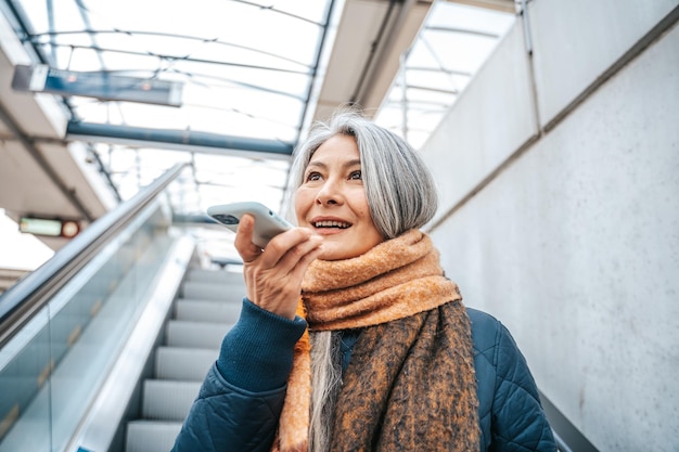 Senior woman in a trail station uses her smartphone