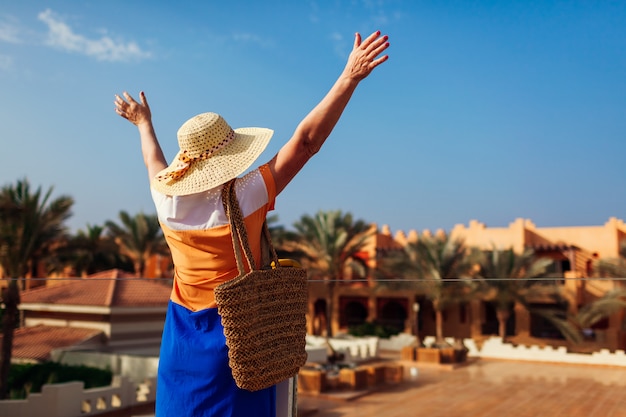 Photo senior woman walking on hotel territory and raising hands.