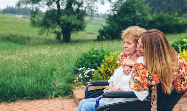 Senior woman in a wheelchair with her daughter in the garden