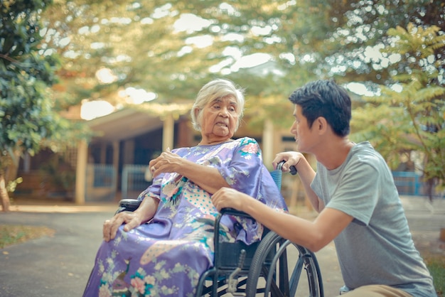 Senior woman with daughter; Nurse taking care of senior woman on wheelchair