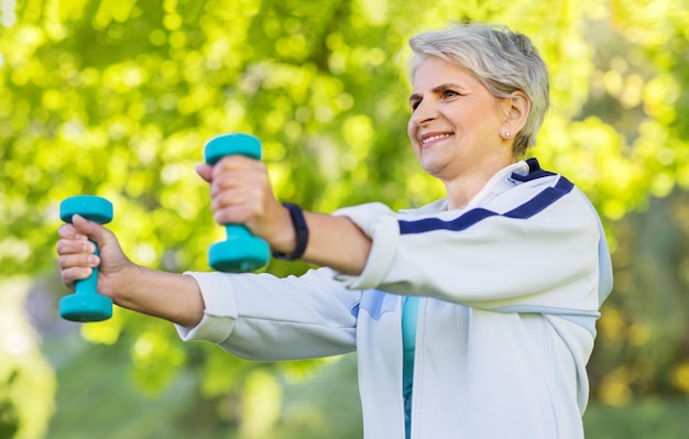 Photo senior woman with dumbbells exercising at park