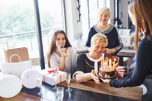 Senior woman with family and friends celebrating a birthday indoors.