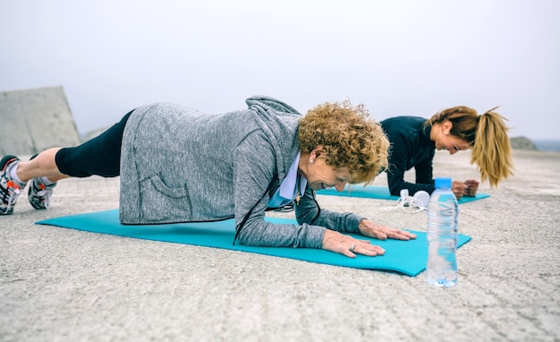 Senior woman with female coach doing plank exercise