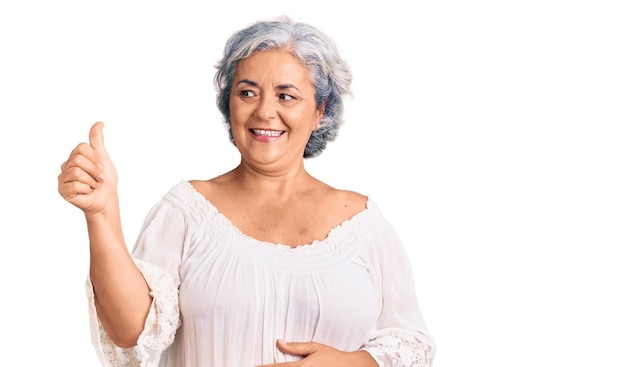 Senior woman with gray hair wearing bohemian style looking proud smiling doing thumbs up gesture to the side