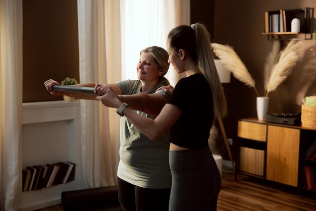 Senior woman with young girl stretching at home indoors using stretching band doing exercises