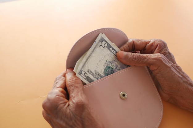 Senior women hand saving cash in wallet